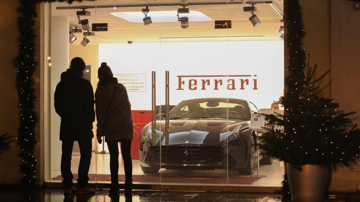 Personas miran un vehículo de lujo en una tienda de Ferrari, en Moscú, Rusia, en diciembre.