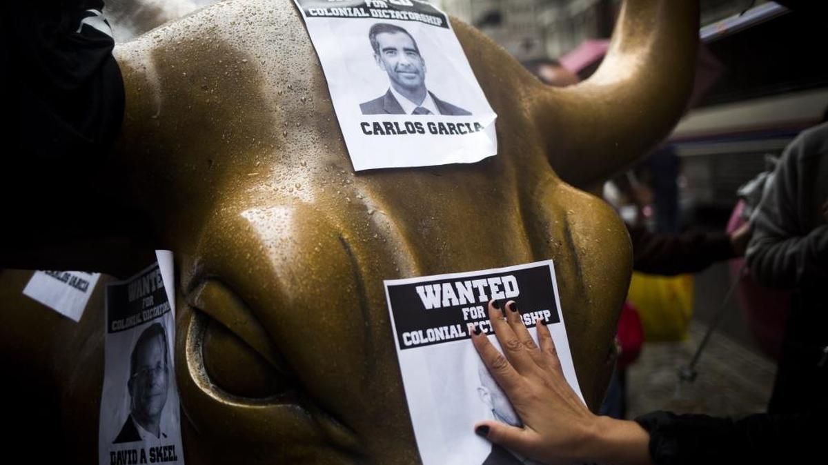 Una manifestantes coloca el viernes avisos de “Buscado” en la estatua del Toro de Wall Street, en Nueva York, en protesta por la Junta de Control Fiscal de Puerto Rico.