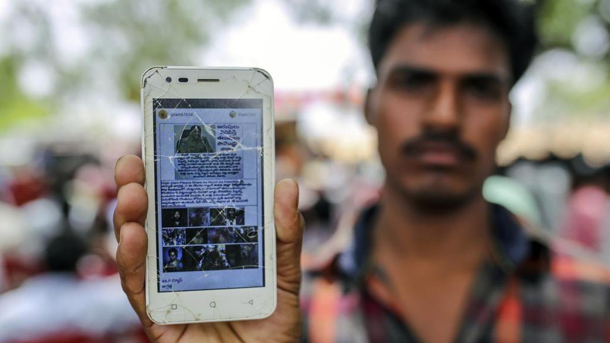 Un hombre sostiene un teléfono móvil que muestra un mensaje falso compartido en el servicio de mensajería de WhatsApp de Facebook mientras asistía a un evento para crear conciencia sobre noticias falsas en la aldea de Balgera en el distrito de Gadwal, Telangana, India, el 12 de junio.