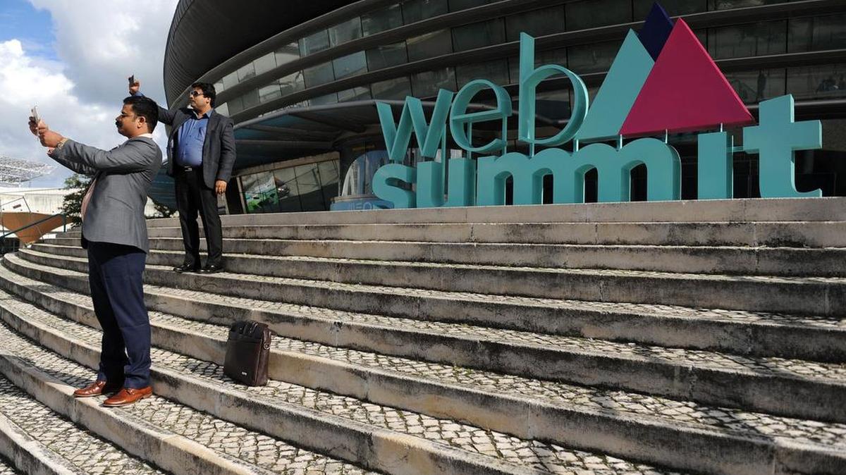 Dos participantes toman fotografías con sus teléfonos frente a la sede de la Web Summit, en Lisboa, Portugal.
