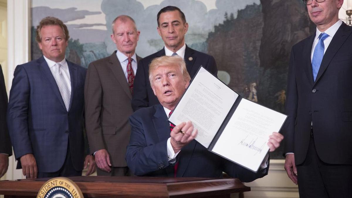 El presidente de los Estados Unidos, Donald J. Trump (cen.), sostiene un memorando que firmó el lunes sobre las leyes, políticas, prácticas y acciones de China relacionadas con la propiedad intelectual, la innovación y la tecnología, en la Casa Blanca.