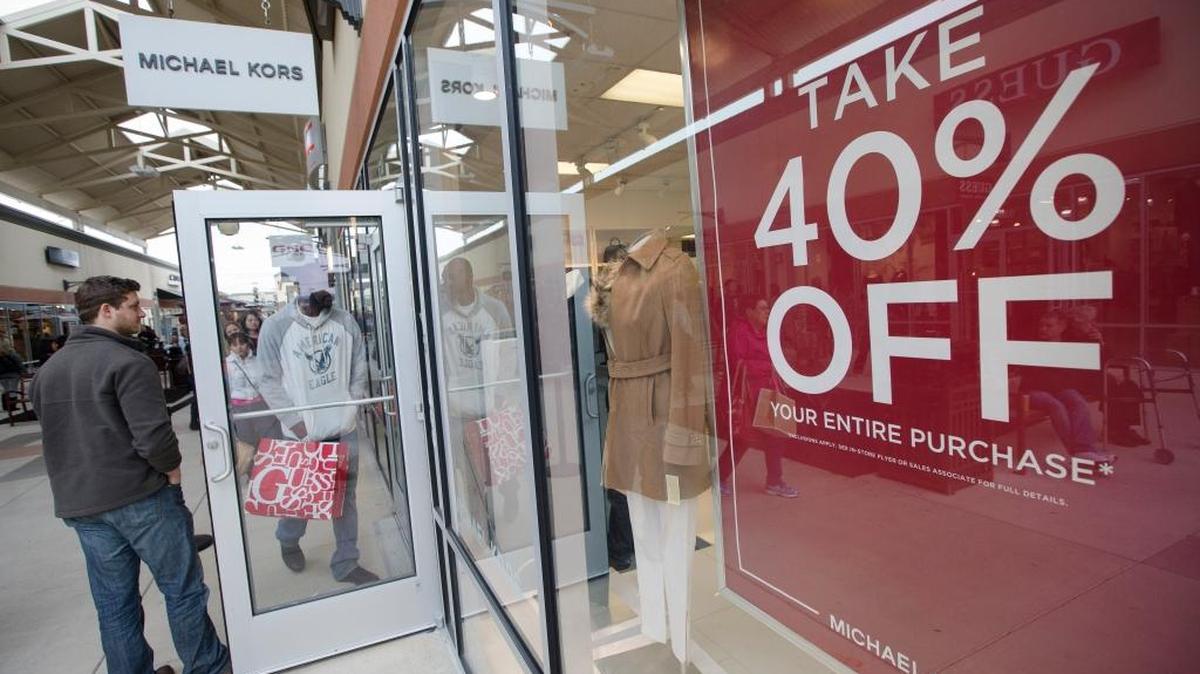 Un portero sostiene tiene la puerta para que un comprador ingrese en una tienda de Michael Kors en Cincinnati Premium Outlets, en Monroe, Ohio. Para aquellos dispuestos a esperar, hay una mejor época del año para comprar todo tipo de cosas, desde televisores de trajes de baño. Foto de archivo.