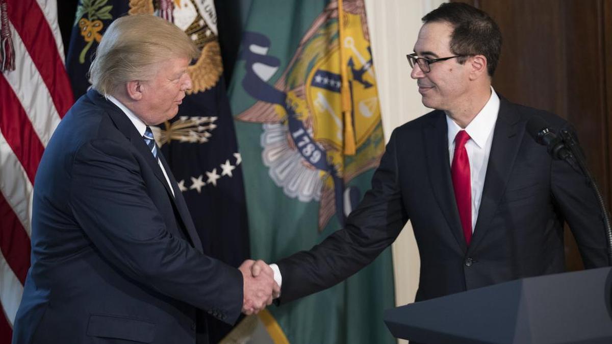 El presidente de EEUU, Donald Trump (izq.) estrecha la mano del secretario del Tesoro, Steven Mnuchin, durante su primera visita al Departamento del Tesoro en Washington.