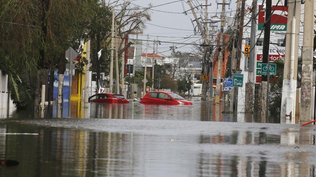 Dos coches flotan en una calle totalmente inundada el viernes 22 de septiembre de 2017, a dos días del paso del huracán María, en San Juan, Puerto Rico.