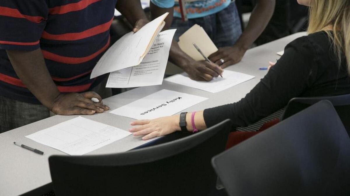 
Una representante de la agencia de Servicios Kelly atiende a las personas que buscan empleo en una feria de trabajo de Dallas, Texas.

