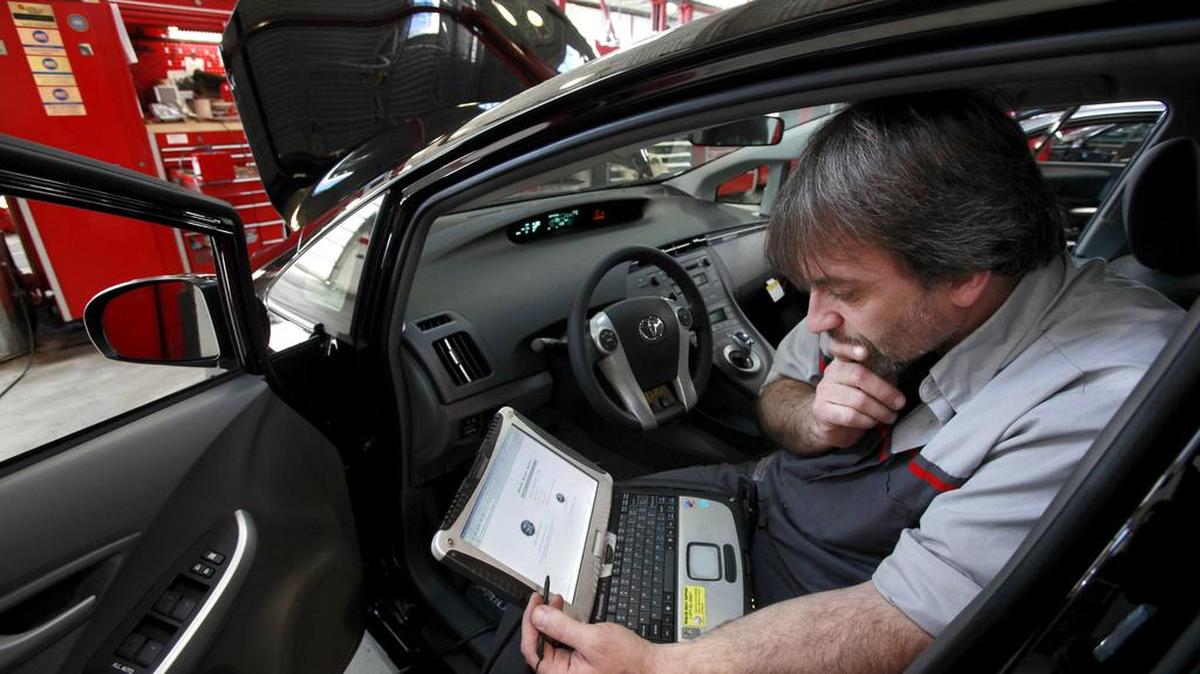 Un técnico utiliza una laptop para diagnosticar y reparar el sistema de frenos de un Toyota Prius 2010.