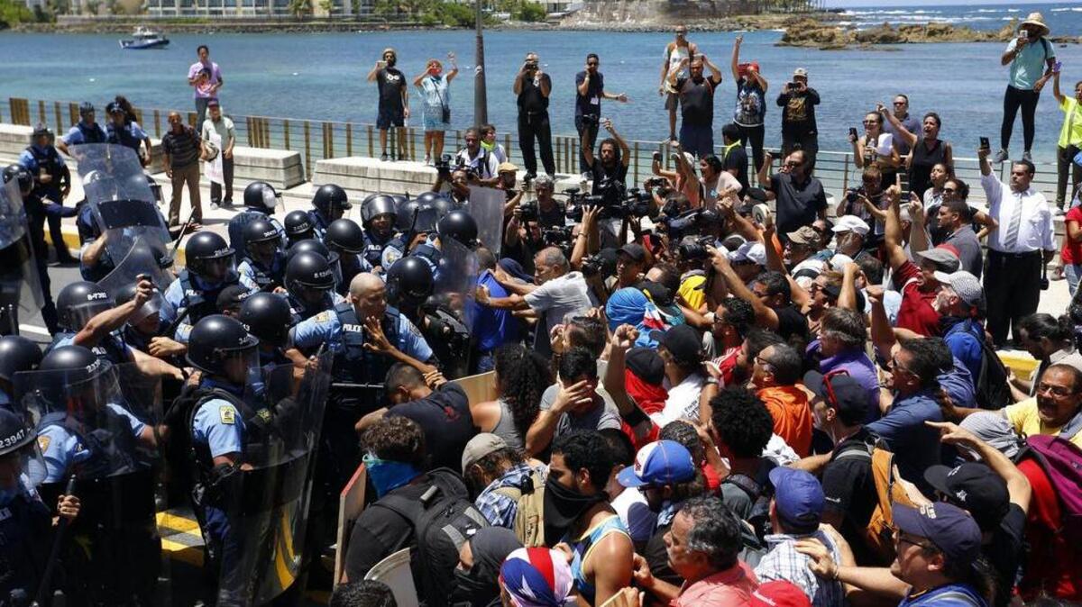 Manifestantes se enfrentan a policías el miércoles en San Juan, en las afueras de donde se celebra la primera conferencia sobre la ley federal conocida como Promesa, en Puerto Rico.