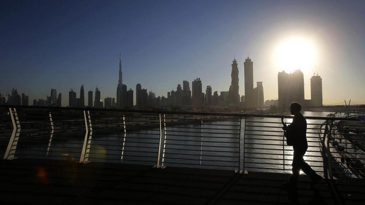 Un hombre cruza un puente peatonal sobre el nuevo Canal Acuático de Dubai.