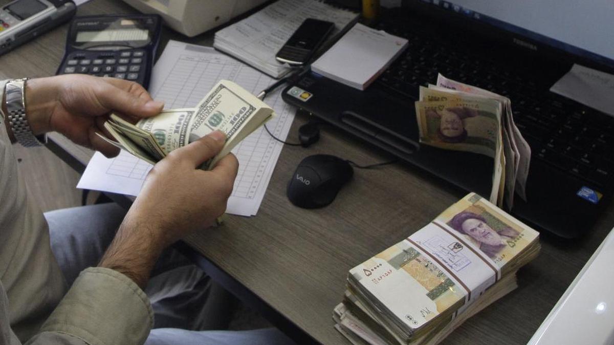 
Un empleado de una casa de cambio de divisas en Teherán cambia dólares por billetes iraníes en esta imagen de archivo.


