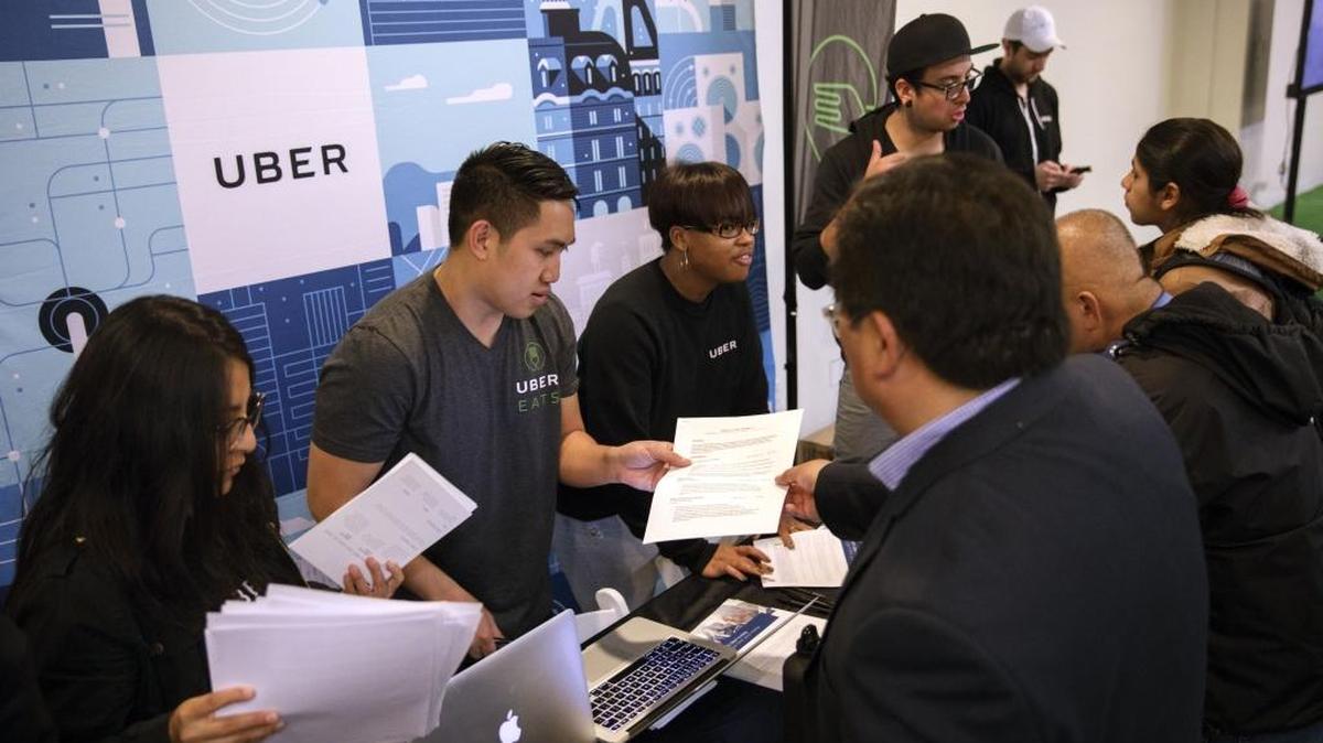 Representantes de Uber Technologies Inc. revisan resumes de personas buscando trabajo en una feria en California.