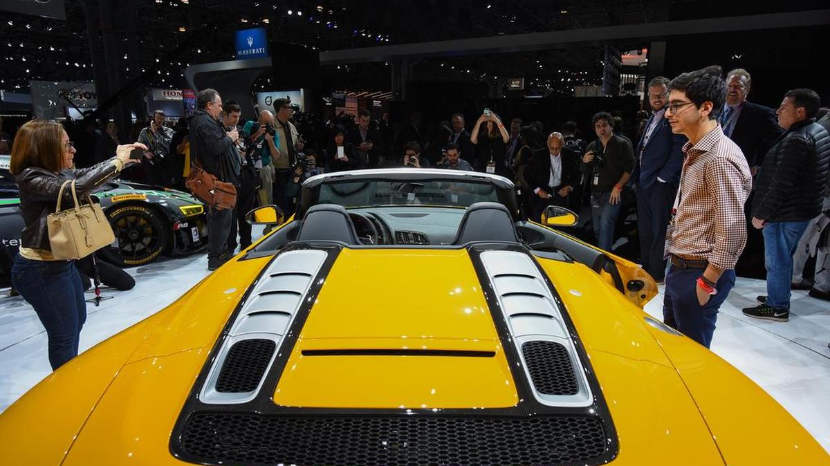 Varias personas admiran el Audi AG R8 Spyder convertible en el Salón Internacional del Auto de Nueva York.