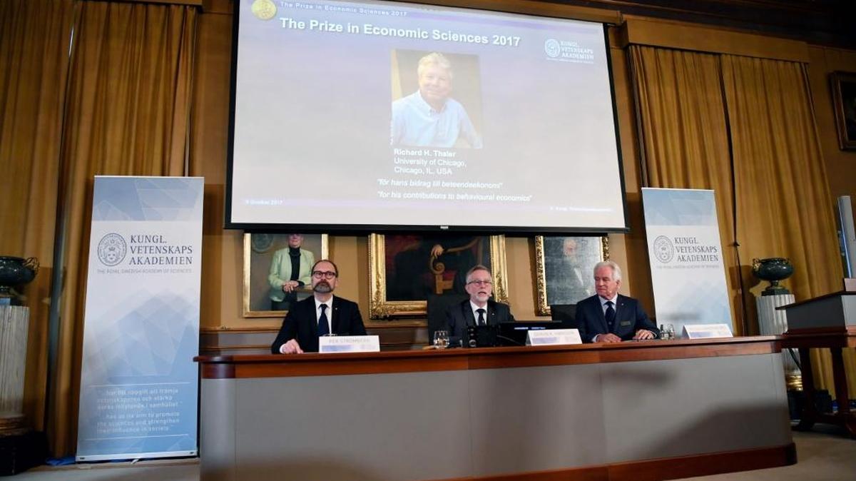 Miembros del Comité del Premio Nobel de Economía anuncian el lunes el ganador del 2017: el estadounidense Richard Thaler (en la pantalla) por los efectos de la psicología en la economía.