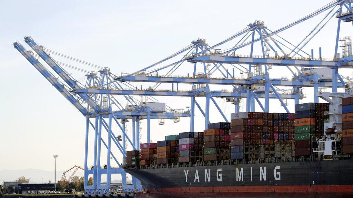 FILE - In this Nov. 4, 2019 file photo cargo cranes are used to take containers off of a Yang Ming Marine Transport Corporation boat at the Port of Tacoma in Tacoma, Wash. The U.S. trade deficit rose in March 2020 as the coronavirus outbreak battered America’s trade with the world. The gap between what the United States sells and what it buys abroad rose 11.6% in March to $44.4 billion from $39.8 billion in February. (AP Photo/Ted S. Warren, File)