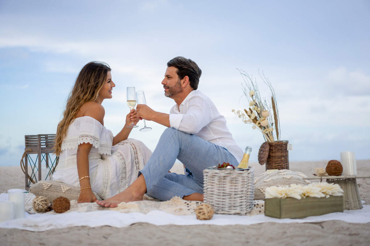 Pareja amorosa en una cita romántica en la playa haciendo un brindis