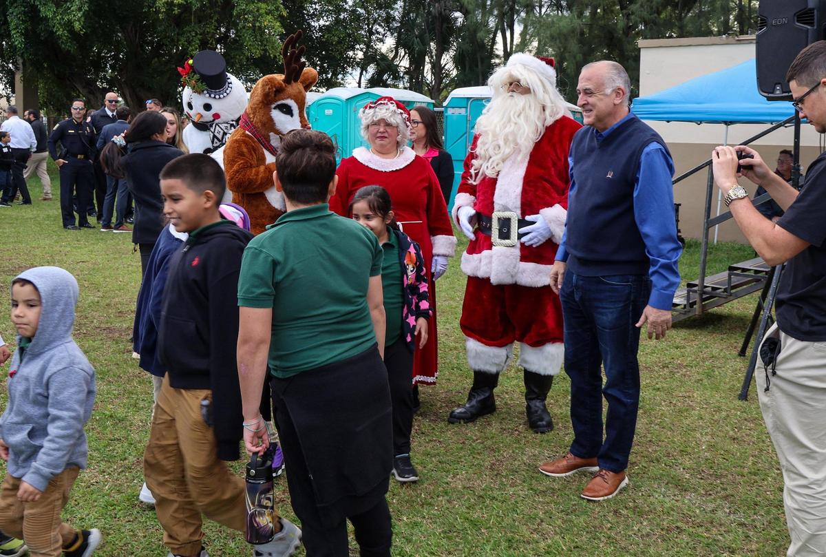 El alcalde Esteban Bovo Jr. se unió a Santa y la Sra. Claus mientras saludaban a los niños después de que llegaron en un helicóptero para entregar regalos a los estudiantes de diferentes escuelas de la ciudad de Hialeah durante un evento de colecta de juguetes en el Hialeah Milander Center, el miércoles 06 de diciembre de 2023.