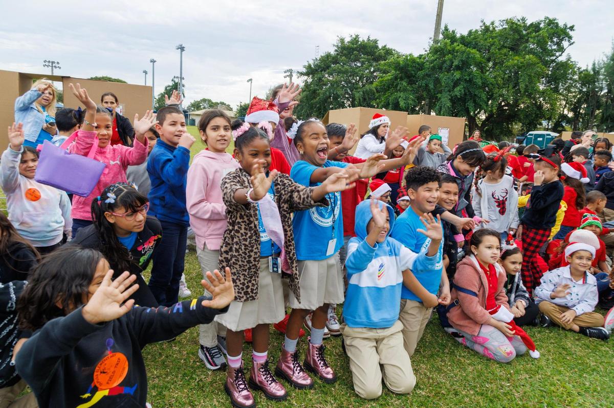 Estudiantes de diferentes escuelas de la ciudad de Hialeah saludan mientras esperaban que Papá Noel y la Sra. Claus llegaran en helicóptero durante un evento de recolección de juguetes, el miércoles 6 de diciembre de 2023.