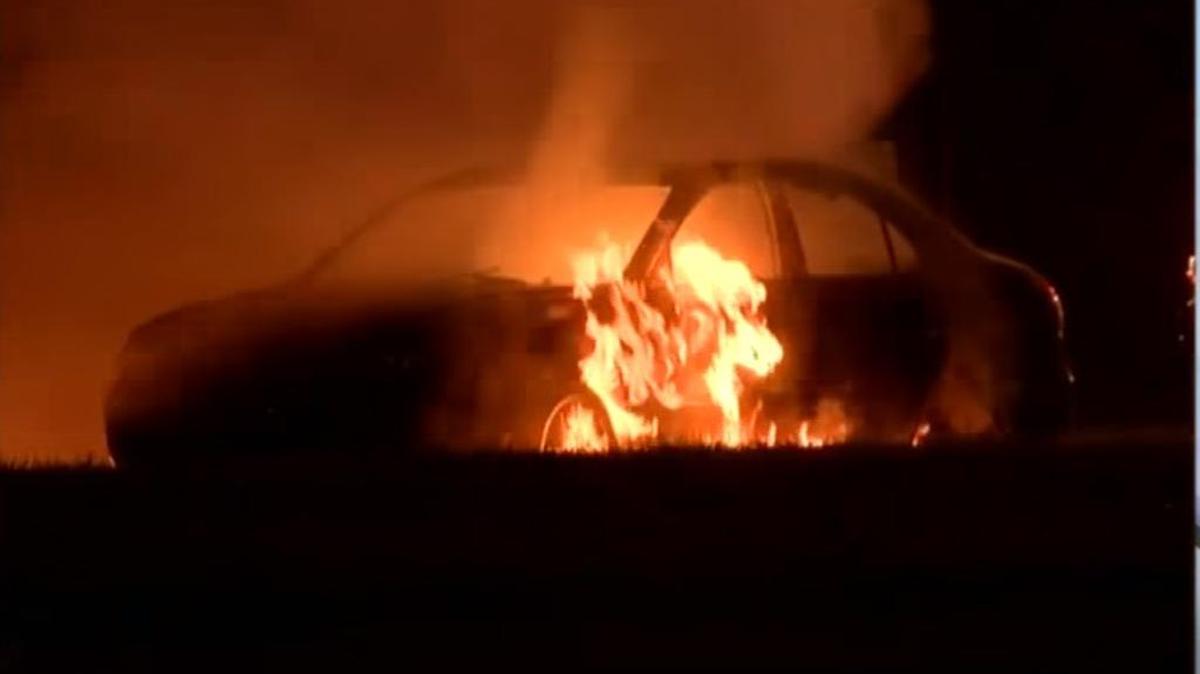 Momento en el que el carro es devorado por las llamas. Bomberos (no en la foto) intentan apagar el incendio.
