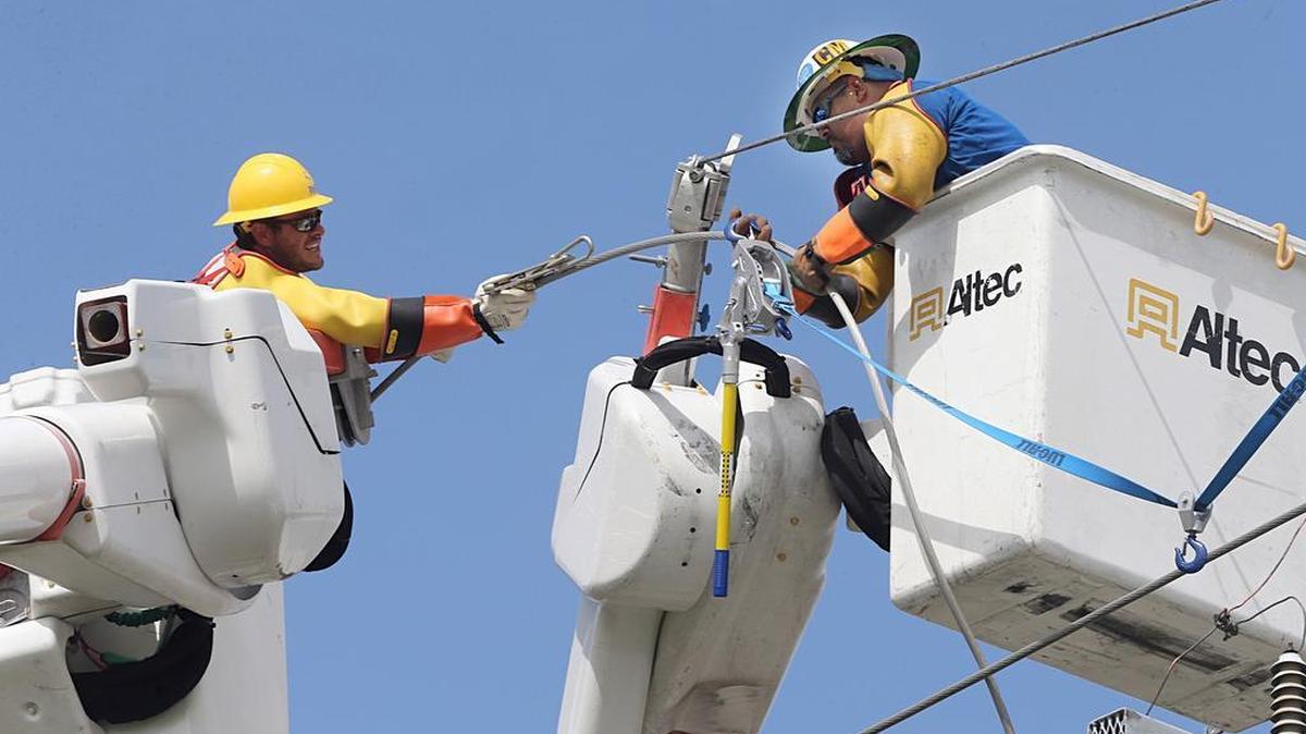 Titus Beaumonan (izq.) y Christ Montiel reparan un generador eléctrico el lunes 11 de septiembre de 2017 en Kendall, Miami.