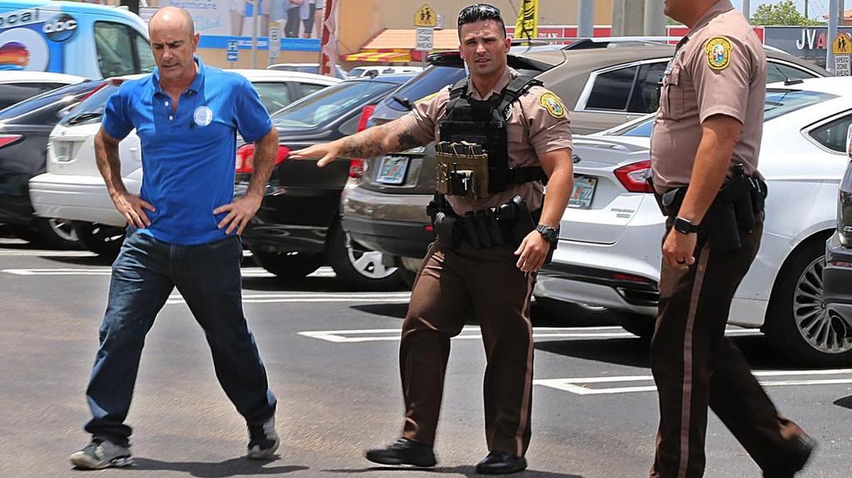 Agentes de policía tratan de restringir a Osmani Hernández, cuya esposa fue una de las víctimas en un tiroteo el sábado en un restaurante en Coral Way, en el oeste de Miami-Dade.