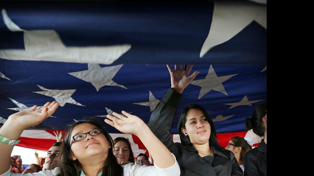 
Valeria Duarte, de 12 años, nacida en Colombia (izq.), e Yvelise Peña, de 17, nacida en Cuba, tocan una bandera de EEUU durante una ceremonia especial de naturalización para menores de edad, el 17 de febrero, en el Parque Nacional Biscayne.

