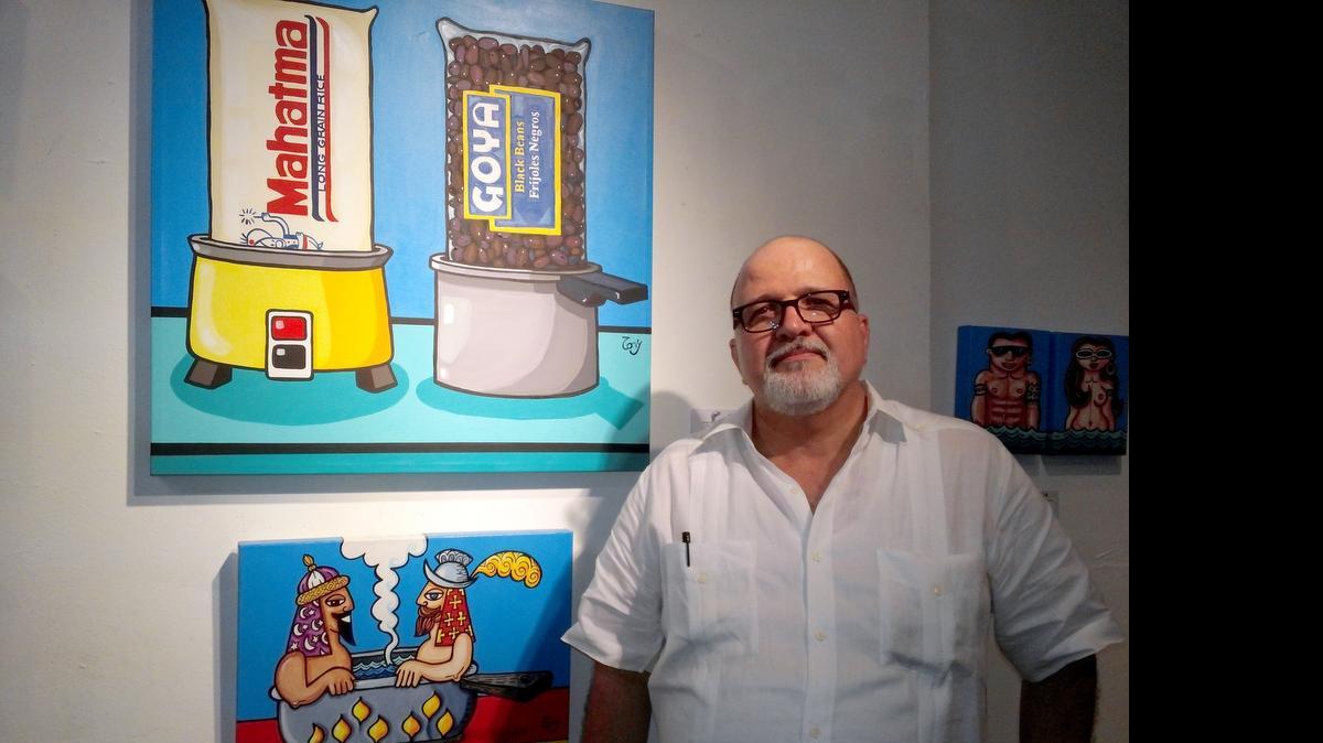 
El artista Tony Mendoza junto a dos de sus obras que definen la cultura culinaria del cubanoamericano en Estados Unidos.
