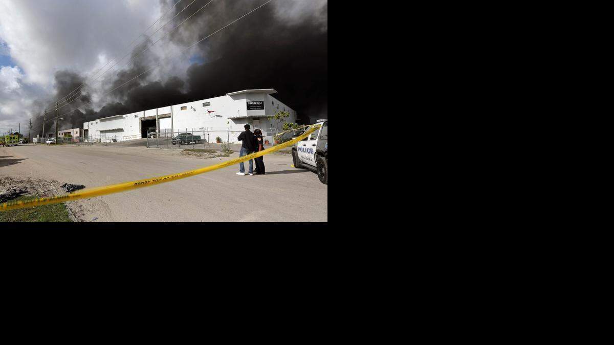 
Dos policias de la ciudad de Opa-Locka observan el incendio en la fabrica de muebles de patio que empezo a las ocho de la ma√±ana el Jueves, Marzo 15, 2015.
