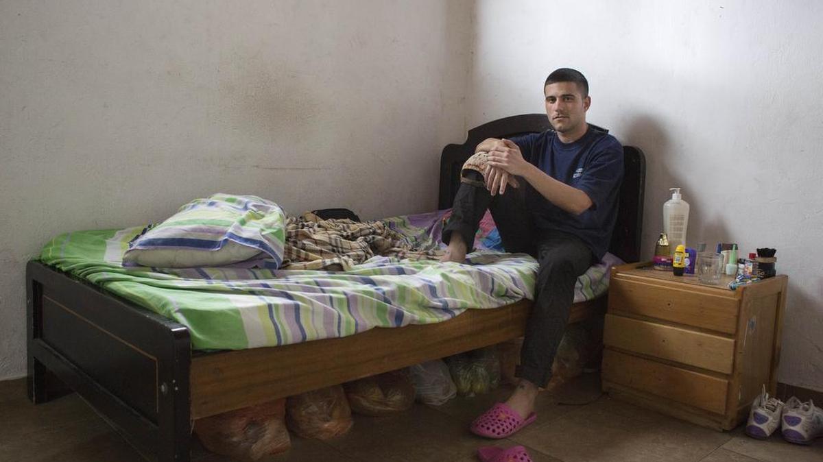 
El optometrista cubano Osniel Hernández Delgado sentado en su cama en una habitación que comparte con otros en Bogotá.
