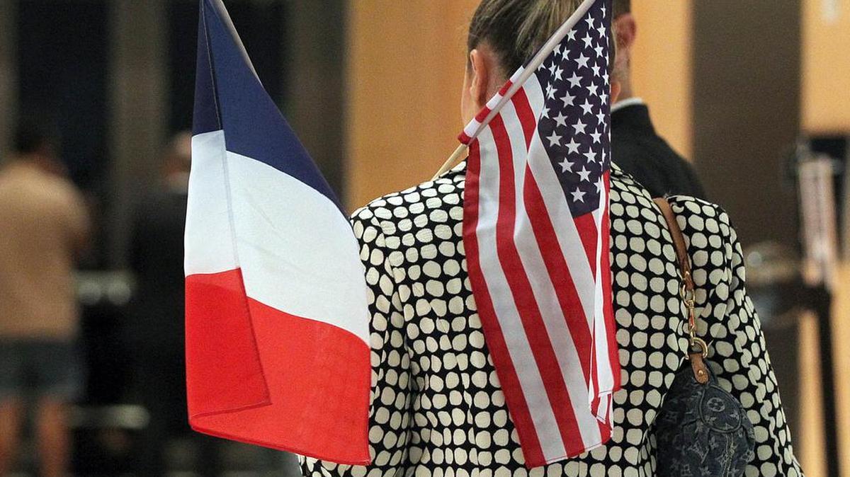 Laurence Segaert sostiene las banderas francesa y norteaméricana al momento de unirse al grupo de Miami Stands with Paris.