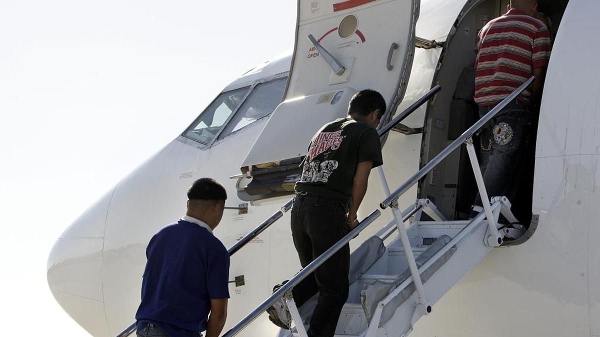 un grupo de mexicanos aborda un avión que los transportó a la frontera con México, tras ser deportados.