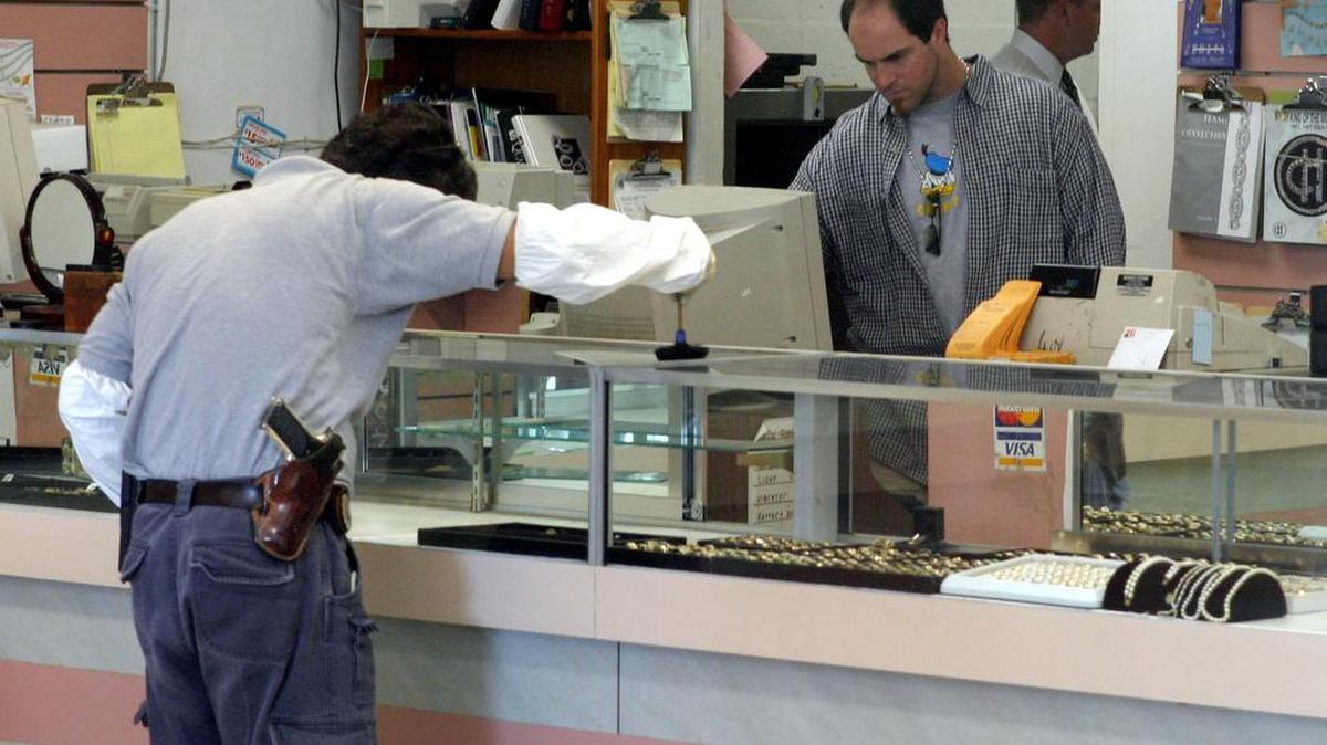 El detective de la Policía de Fort Lauderdale, Juan Cabrera, busca huellas dáctilares en mostradores de joyas donde ladrones se robaron más de $50,000 en joyas de Payless Jewelry and Pawn. Foto de archivo.