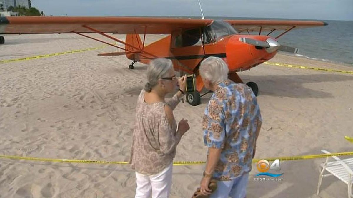 
Una pareja toma una foto del avión Piper J5A que aterrizó de emergencia el jueves en la playa de Pompano Beach. 
