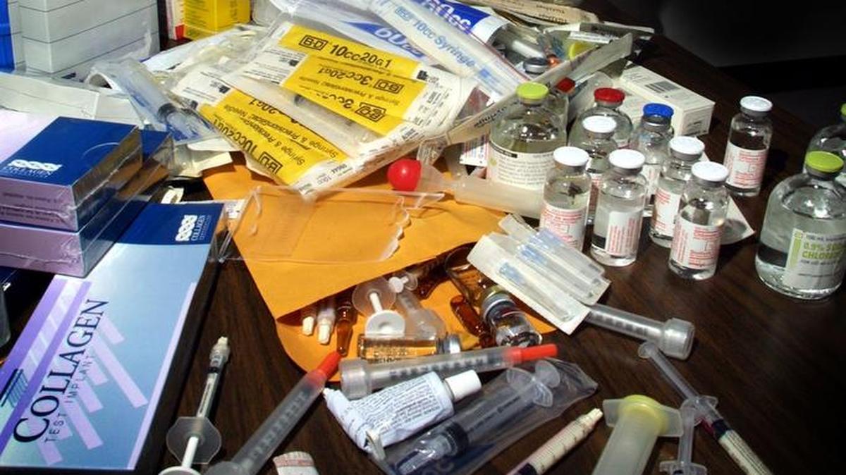 Un oficial del Departamento de Salud de la Florida examina una jeringa que forma parte de parafernalia confiscada que tiene que ver con inyecciones ilegales de silicona. Foto de archivo.