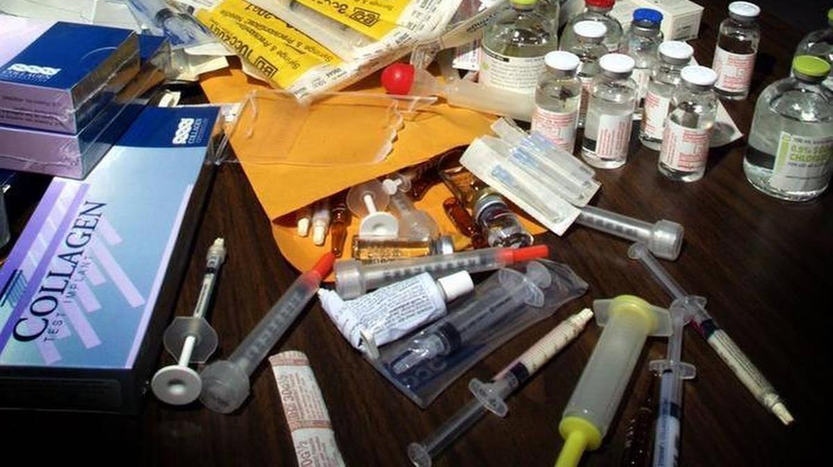 Un oficial del Departamento de Salud de la Florida examina una jeringa que forma parte de parafernalia confiscada que tiene que ver con inyecciones ilegales de silicona. Foto de archivo.