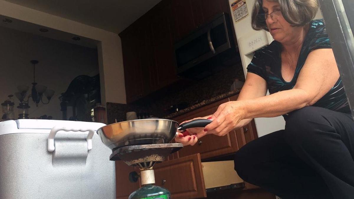 Elena Rivera prepara la comida de su familia en una cocina portátil, debido al corte del fluido eléctrico en el edificio donde vive con su familia, en Hialeah. El inmueble sufrió el incendio de parte del techo, tras ser alcanzado por un rayo la semana pasada.