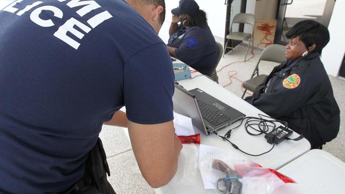El agente Raynier Rodriguez inspecciona algunas de las armas que fueron entregadas el sábado en Miami.