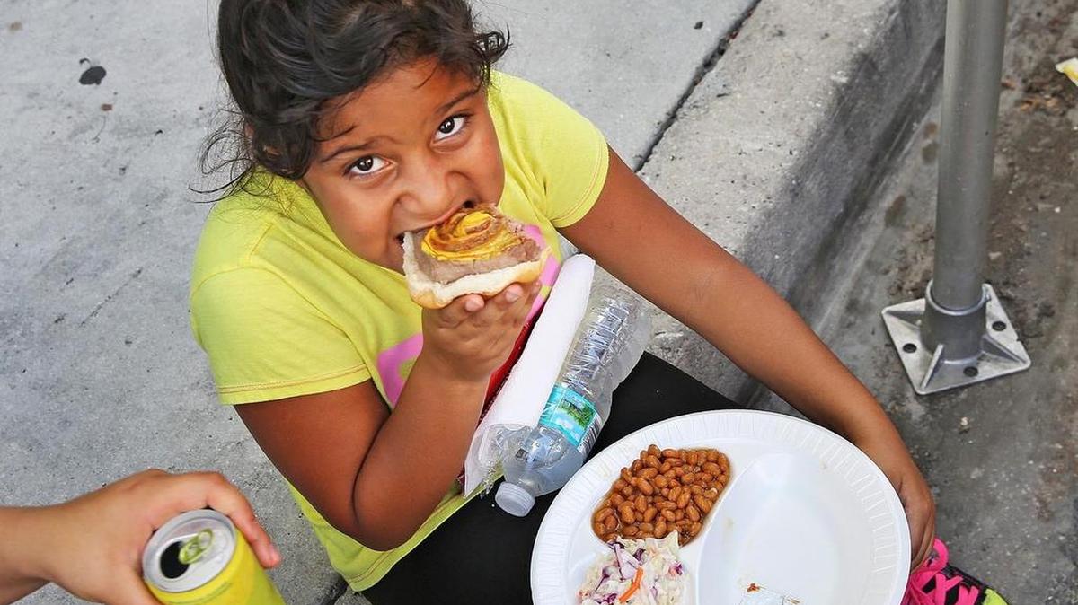Andrea Parra, de 7 años, disfruta su comida gratuita el viernes en el evento “Navidad en julio” del Miami Rescue Mission and Broward Outreach Centers.