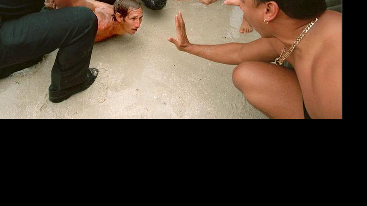Foto de archivo que muestra a dos policías de Surfside deteniendo a un balsero cubano que había evadido al Guardacostas y trataba a toda costa llegar a la playa para poder quedarse en el país. Una personas que presenció el incidente en la playa la pide al balsero calmarse. “¡Tranquilo, que ya llegaste!”, le dijo. El incidente ocurrió el 29 de junio de 1999.