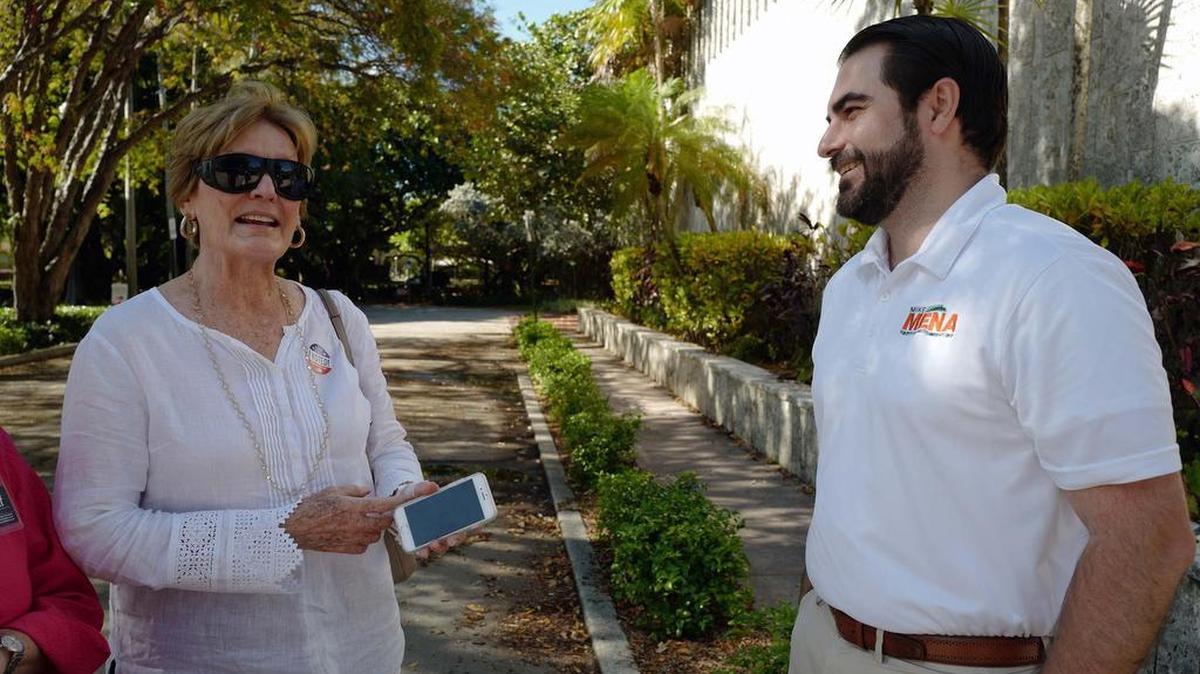 Mike Mena (derecha ) saluda a la residente Julie Connor en el precinto de la Biblioteca de Coral Gables, el martes, 25 de abril del 2017.