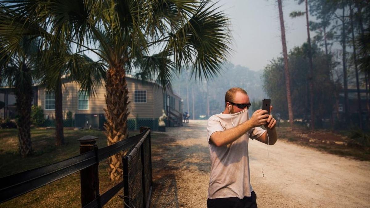 Un hombre se cubre la cara durante una zona cerca a un incendio forestal en Naples, Florida.