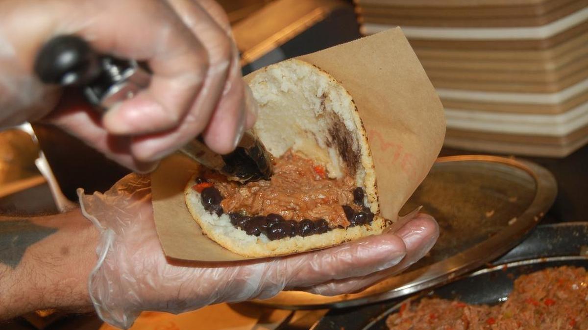 
Preparando una arepa rellena de carne “esmechada” y caraotas (frijoles) negras. Estos dos platos son rellenos tradicionales en las arepas.
