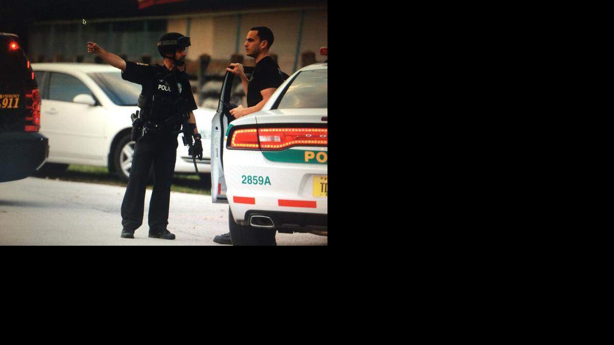 
Dos agentes de policía vigilan cerca de la secundaria Miami Carol City Senior, NW 33 Court y 187 Street, en donde el jueves un tiroteo dejó dos jóvenes heridos. 

