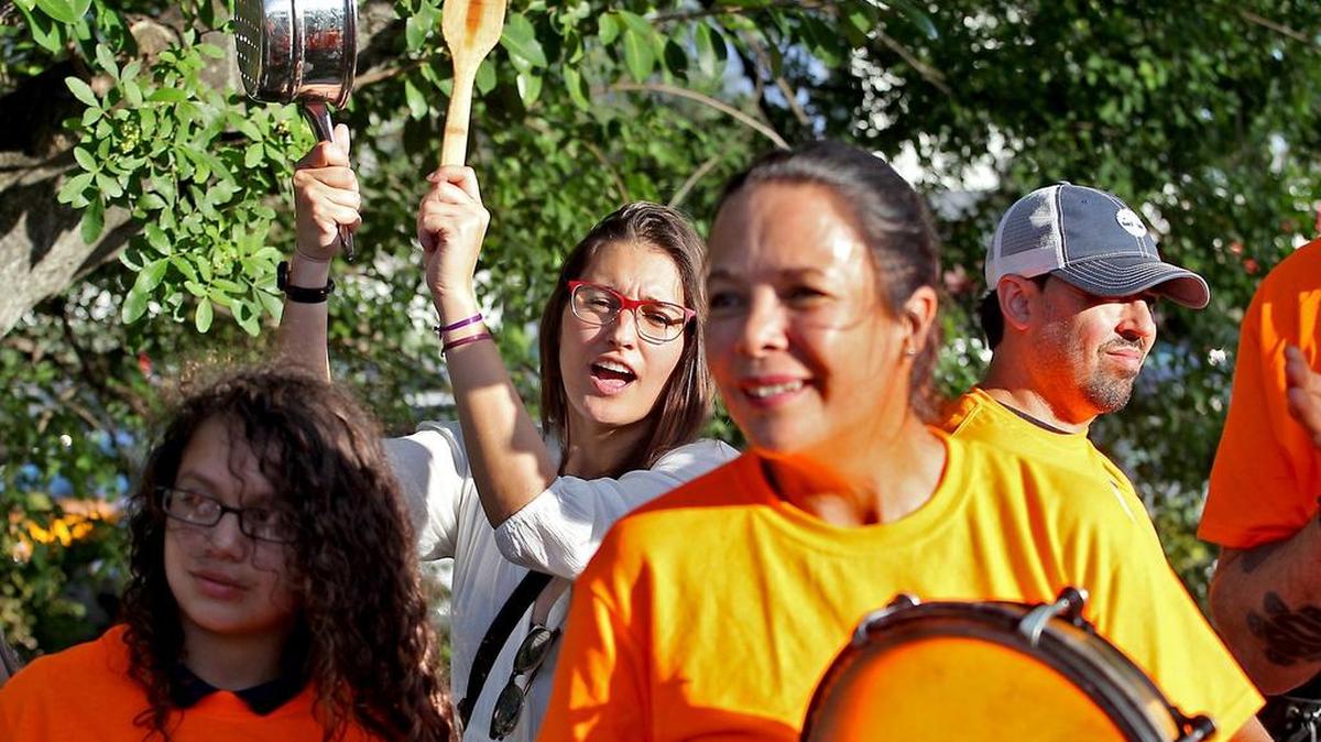 Daniela Martins 28 (en el centro, en blanco) de Bolivia se une a un grupo de inmigrantes que protestaban con cacerolazos en las afueras del campo de golf de Trump el martes 18 de octubre de 2016.
