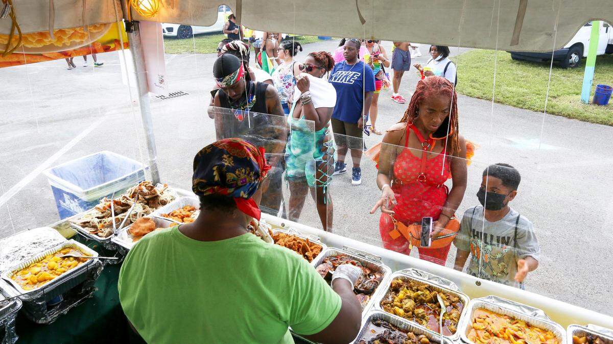 Personas ordenan comida en la carpa de cocina jamaicana durante el Carnaval de Miami 2021, el primer carnaval del Caribe norteamericano ese año, en el recinto ferial del condado de Miami-Dade en Miami, Florida, el domingo 10 de octubre de 2021