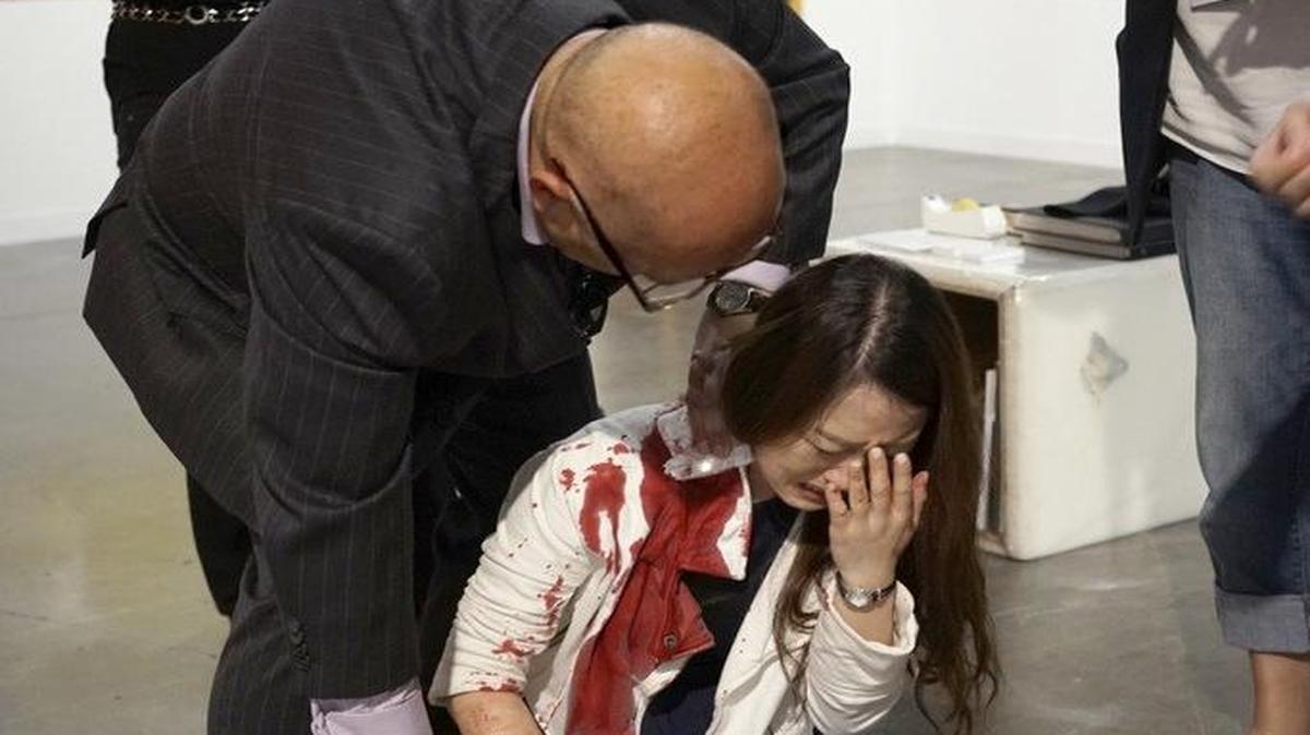 Un hombre comprueba el pulso de una mujer apuñalada durante la exposición de Art Basel en el Centro de Convenciones de Miami Beach el 4 de diciembre de 2015.