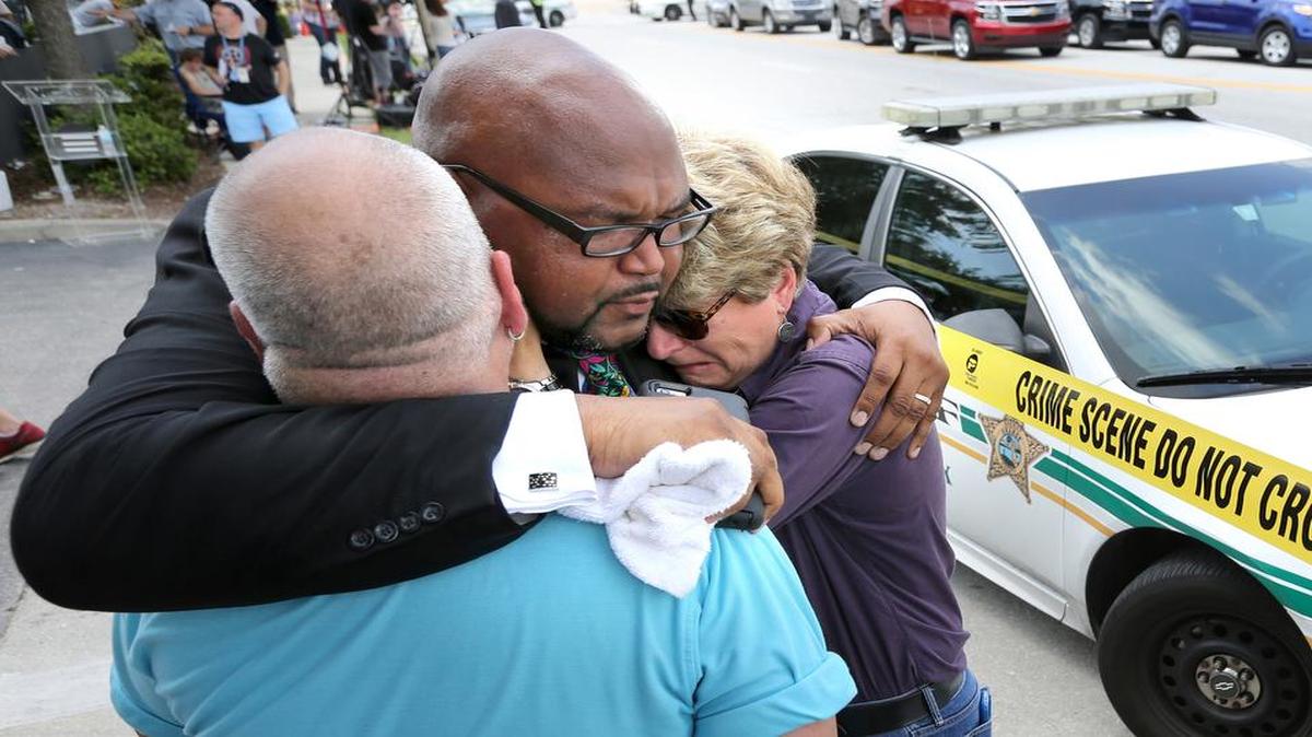 Kelvin Cobaris, un pastor local, consuela a Patty Sheehan, comisionada de la Ciudad de Orlando, y a Terry DeCarlo, activista por los derechos de los gays en Orlando, tras el atentado que dejó al menos 50 muertos el domingo.