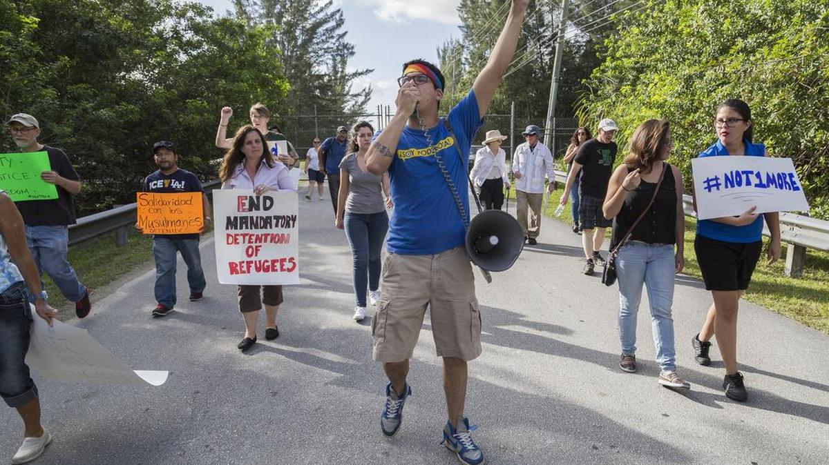 Con megáfono en mano, Gabriel García-Vera (centro) lidera al grupo de activistas que gritan consignas durante la protesta afuera del Centro de detención de Krome el domingo.