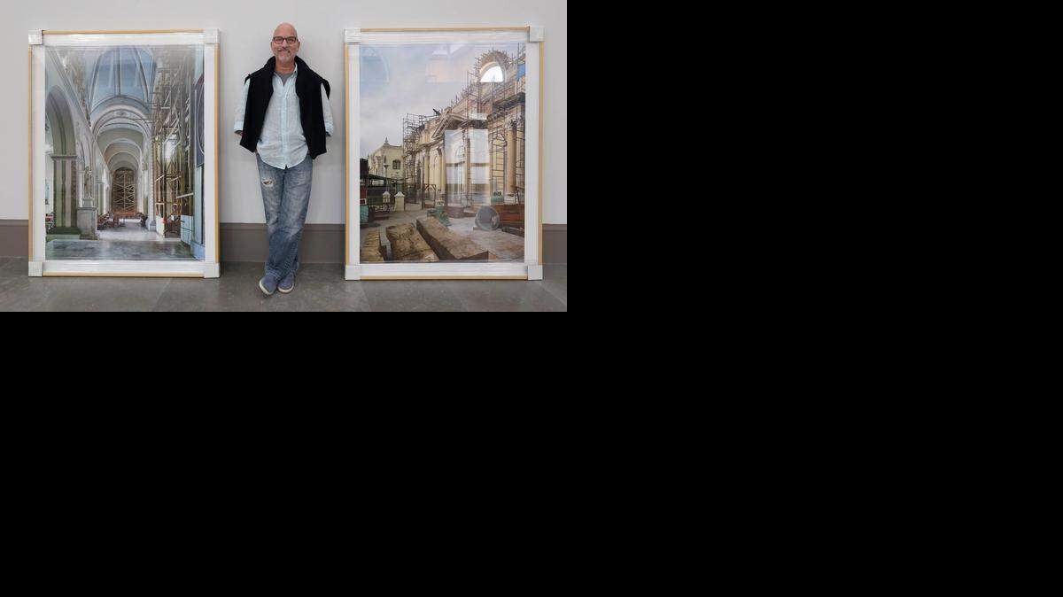 
El fotógrafo cubanoamericano Carlos Domenech en Coral Gables Art Museum junto a algunas de las fotos de iglesias de Santiago de Cuba que tomó en un viaje a la isla en el 2013. 
