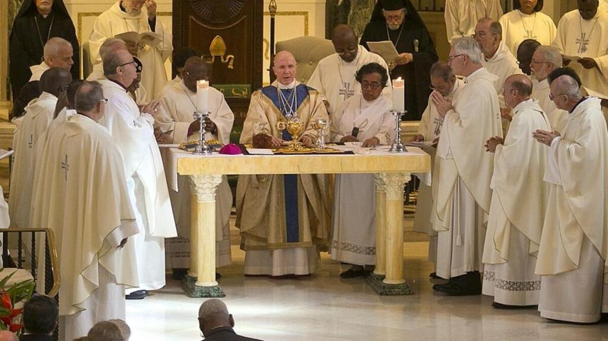 El recién investido obispo Peter Eaton, centro, durante la ceremonia de la repartición de los panes en la catedra episcopal Trinity el sábado .