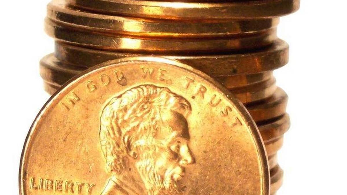 Una pila de monedas estadounidenses de un centavo, con otra moneda del mismo valor en frente.