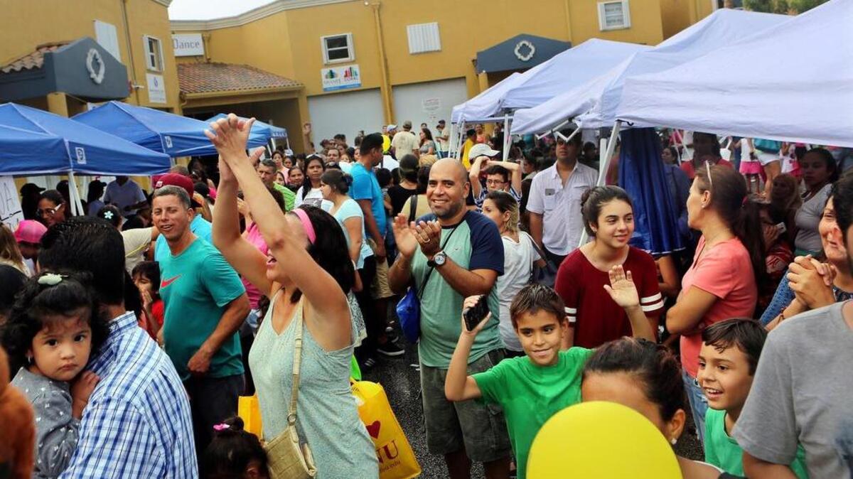 Los asistentes al evento “Operation Backpack” organizado por Toys For Kids Miami cantan y bailan mientras esperaban los morrales con los útiles escolares que la organización les dio.